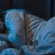 Vrouw ligt wakker in bed met hand op pijnlijke schouder door nachtelijke schouderklachten bij Fysiopark Uden