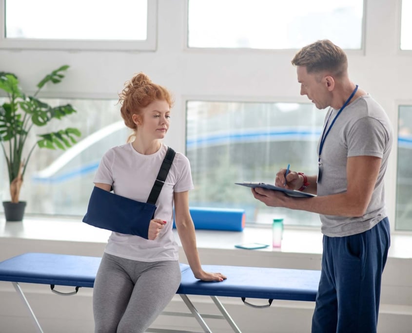 Leefstijl en herstel bij fysiotherapie Patiënt met arm in mitella bespreekt haar herstel met een fysiotherapeut.