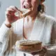 Vrouw die 's avonds in de keukenkast naar iets lekkers zoekt, emotie-eten